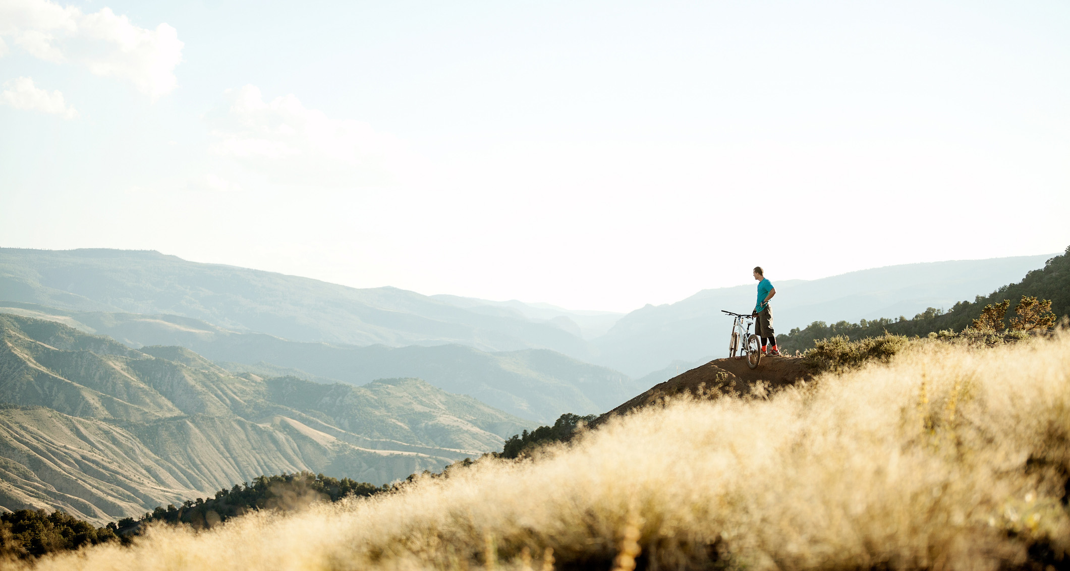 Cyclist standing on the hill and looking at the mountains scenery